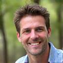 Close-up portrait of David L., a man in his 30s, outdoors with a slight smile.